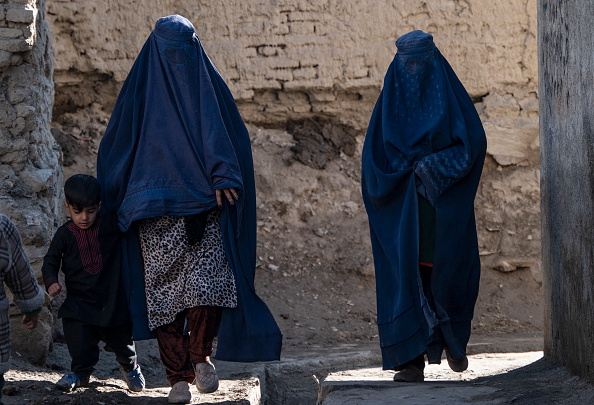 Des femmes afghanes vêtues de burqa marchent avec un enfant dans le quartier de Koch-e Asheqani Arefan à Kaboul, le 31 janvier 2024. (Photo WAKIL KOHSAR/AFP via Getty Images)