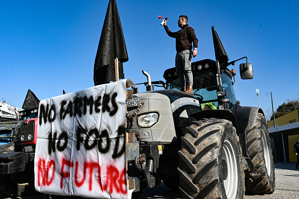 Un homme se tient sur son tracteur alors que les agriculteurs se rassemblent, avec leurs tracteurs, à la foire agricole Agrotica à Thessalonique. (Photo SAKIS MITROLIDIS/AFP via Getty Images)