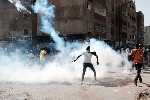 Un manifestant rejette une bombe lacrymogène lors d'affrontements avec la police en marge d'une manifestation à Dakar, le 9 février 2024. (Photo GUY PETERSON/AFP via Getty Images)