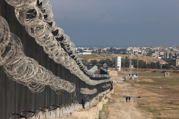 Des Palestiniens déplacés marchent près de la barrière frontalière entre Gaza et l'Égypte, le 16 février 2024 à Rafah. (Photo MOHAMMED ABED/AFP via Getty Images)