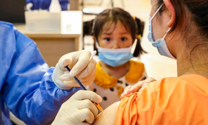 Un enfant regarde une femme se faire vacciner contre le Covid-19 par le China National Biotec Group (CNBG) à Nantong, dans la province chinoise du Jiangsu (est), le 5 juillet 2021. (STR/AFP via Getty Images)