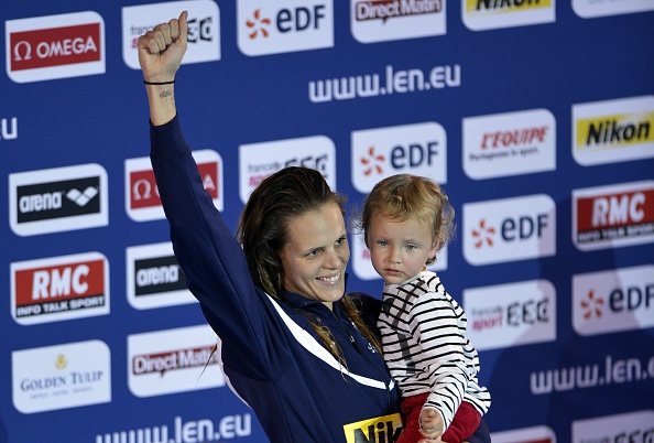 Laure Manaudou pose avec sa fille Manon sur le podium après avoir remporté l'épreuve féminine du 50 m dos aux Championnats d'Europe de natation, le 24 novembre 2012, à Chartres. (Photo ÉRIC FEFERBERG/AFP via Getty Images)