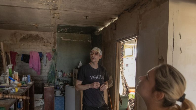Maksym, 33 ans, (à g.) et sa femme Natasha, 39 ans, visitent leur appartement qui a été lourdement endommagé lors d'une récente attaque russe sur la ville, à Kharkiv, le 9 avril 2024, au milieu de l'invasion russe de l'Ukraine. (Photo ROMAN PILIPEY/AFP via Getty Images)