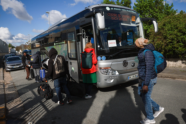 Des migrants arrivent avec leurs affaires pour prendre un bus vers le centre d'accueil pour migrants de Sucy-en-Brie, le 17 avril 2024. (Photo EMMANUEL DUNAND/AFP via Getty Images)