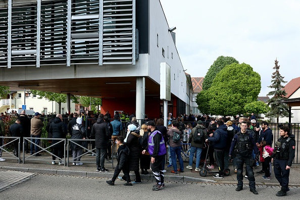 Des élèves et des parents se rassemblent devant une école au milieu des forces de police dans la ville de Souffelweyersheim, le 18 avril 2024. (FREDERICK FLORIN/AFP via Getty Images)