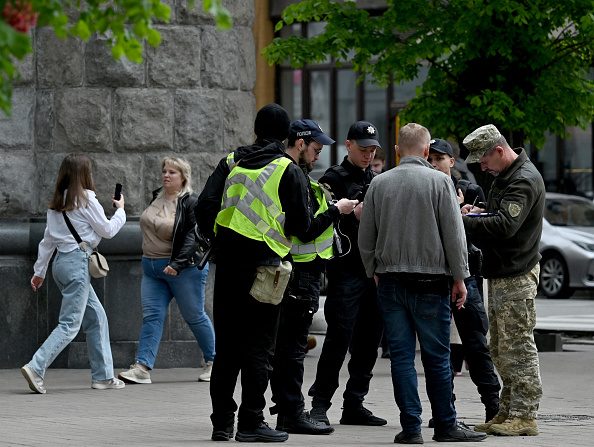 Des militaires et des policiers ukrainiens vérifient les documents d'un homme dans le centre de Kiev, le 25 avril 2024. (Photo SERGEI SUPINSKY/AFP via Getty Images)