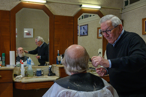 Le coiffeur Roger Amilhastre (à dr.), 90 ans, coupe les cheveux d'Yves Desdoit dans son salon, à Saint-Girons, le 16 avril 2024. (Photo ED JONES/AFP via Getty Images)