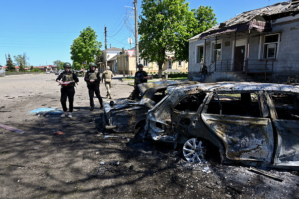 Des policiers ukrainiens inspectent des voitures détruites sur le site d'une attaque, dans le village de Zolochiv, à Kharkiv. (Photo SERGEY BOBOK/AFP via Getty Images)