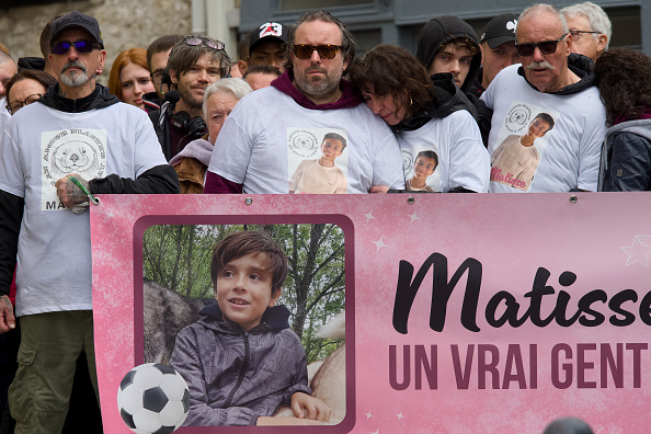 De g. à dr. : Le père, la mère, derrière une banderole à son effigie, participent à une « Marche Blanche » commémorative en hommage à leur fils de 15 ans, Matisse. (GUILLAUME SOUVANT/AFP via Getty Images)