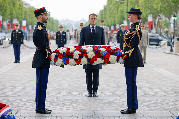 Le président Emmanuel Macron (au c.) dépose des fleurs sur la tombe du Soldat inconnu dans le cadre des cérémonies marquant la fin de la Seconde Guerre mondiale en Europe, à Paris, le 8 mai 2024. (Photo JOHANNA GERON/POOL/AFP via Getty Images)
