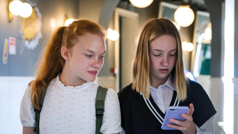 Illustration - Des adolescentes regardent un téléphone portable pendant une pause sur le campus scolaire. Nimito/Gettyimages