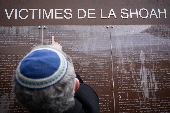 Un homme cherche un nom sur le mur des noms pour « Les victimes de la Shoah du Bas-Rhin » lors de l'inauguration des jardins du souvenir à Strasbourg, le 27 janvier 2025. (SEBASTIEN BOZON/AFP via Getty Images)