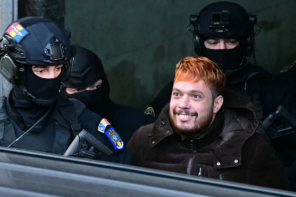 Le condamné français et trafiquant de drogue Mohamed Amra (à dr.) est escorté par des policiers hors de la Cour d'appel de Bucarest le 23 février 2025, à l'issue d'une audience, un jour après son arrestation en vertu d'un mandat d'arrêt européen. (DANIEL MIHAILESCU/AFP via Getty Images)
