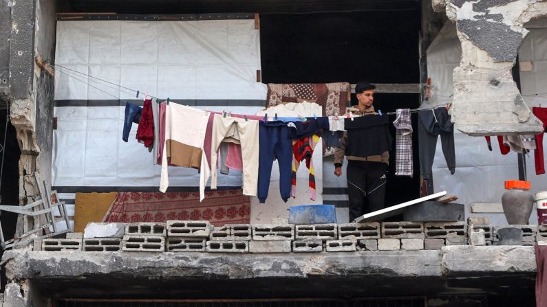Un Palestinien se tient sur le balcon d'un bâtiment endommagé où il s'est réfugié à Beit Lahia, dans le nord de la bande de Gaza, le 9 mars 2025. (Omar al-Qattaa/AFP via Getty Images)