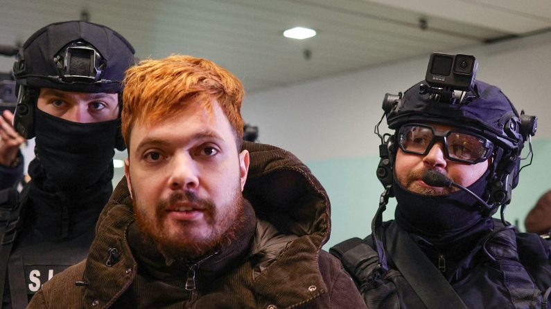 Le trafiquant de drogue français Mohamed Amra escorté par des policiers à l'aéroport international Henri Coanda à Otopeni près de Bucarest, en Roumanie, le 25 février 2025. (OCTAV GANEA/AFP/INQUAM PHOTOS/AFP via Getty Images) 