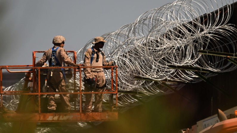 Des militaires américains installent du fil barbelé concertina au sommet du mur le long de la frontière américano-mexicaine entre San Diego et Tijuana, près du port d'entrée de San Ysidro à San Diego, le 23 avril 2025. (Patrick T. Fallon/AFP via Getty Images)