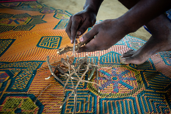 Un homme épluche la racine d’iboga lors de la cérémonie de l’Appel Sacré du Bois Sacré, dans le village de Ndossy, à Akanda, le 13 février 2025. (NAO MUKADI/AFP via Getty Images)