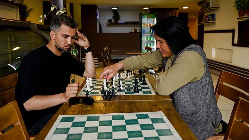 Azizullah Gulzada (à dr.), propriétaire du Cupcake Coffee Shop joue aux échecs avec un ami dans son café à Kaboul le 11 mai 2025. (WAKIL KOHSAR/AFP via Getty Images)