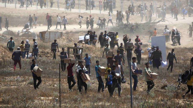 Des Palestiniens déplacés transportant des fournitures de secours reviennent d'un centre de distribution d'aide dans le centre de la bande de Gaza, le 29 mai 2025. (EYAD BABA/AFP via Getty Images)