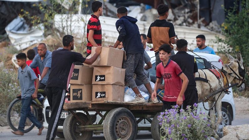 Des personnes transportent des secours sur un chariot de la Fondation humanitaire de Gaza (GHF), une organisation humanitaire privée soutenue par les États-Unis le 8 juin 2025. (EYAD BABA/AFP via Getty Images)