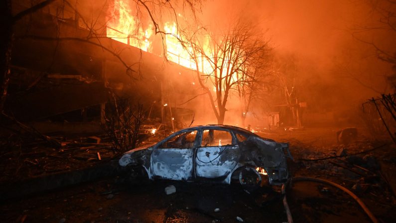 Une voiture brûlée est photographiée devant une maison en feu suite à une attaque de drone russe à Kharkiv le 11 juin 2025, dans le cadre de l'invasion russe en Ukraine. (SERGEY BOBOK/AFP via Getty Images) 