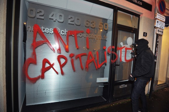A member of the Antifa extremist group vandalizes a storefront in Nantes, France, on Feb. 14, 2014. (FRANK PERRY/AFP/Getty Images)