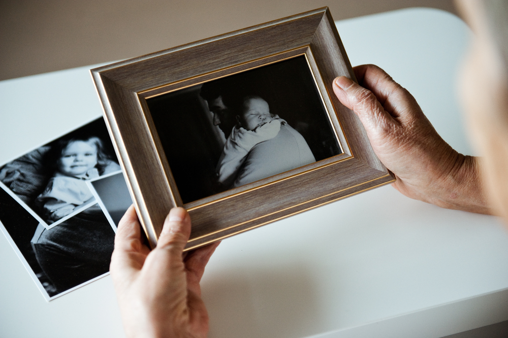 An,Elderly,Woman,Is,Holding,A,Frame,With,A,Black